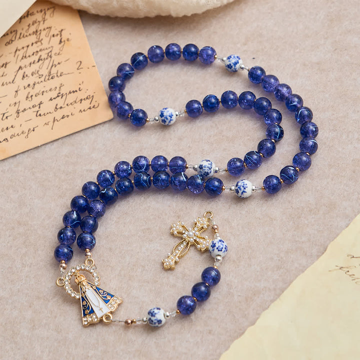 Christianartworkshop Rosenkranz aus tiefblauem, gesprungenem Glas und Porzellanperlen mit einem Mittelstück der Muttergottes von Aparecida - Unsere Liebe Frau und das Kruzifix - image 0