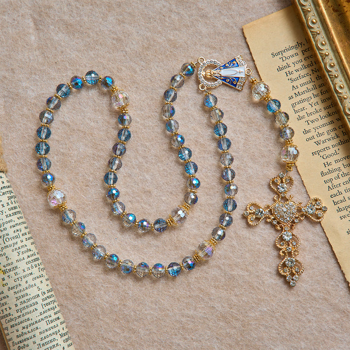 Christianartworkshop Rosenkranz aus schimmernden blauen Perlen mit der Muttergottes von Aparecida und Strasskreuz: Personalisierte Namensperlen als Erinnerungsstück für die Kapelle - image 3
